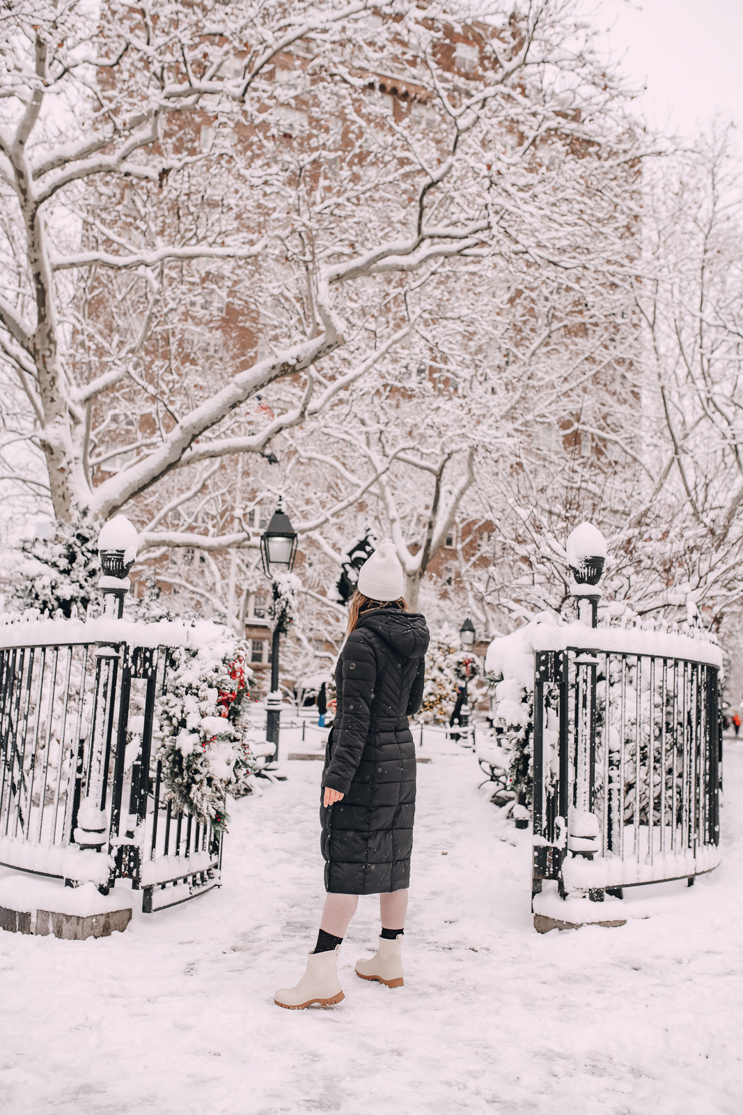 woman wearing long black coat and boots in the snow